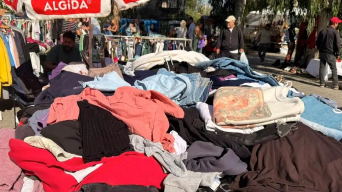 Çalış ikinci el pazarında tezgâhta sergilenen giyim ürünleri ve ziyaretçiler
