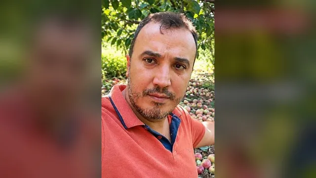Seydikemer Arsa Mahallesi Muhtarı Cüneyt Uçar yere dökülmüş elmaları gösteriyor