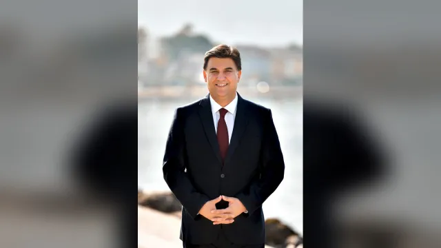 Fethiye Belediye Başkanı Alim Karaca deniz kenarında gülümseyerek poz veriyor