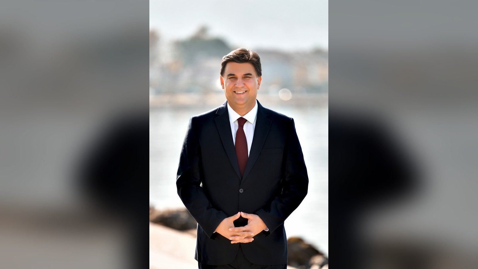Fethiye Belediye Başkanı Alim Karaca deniz kenarında gülümseyerek poz veriyor