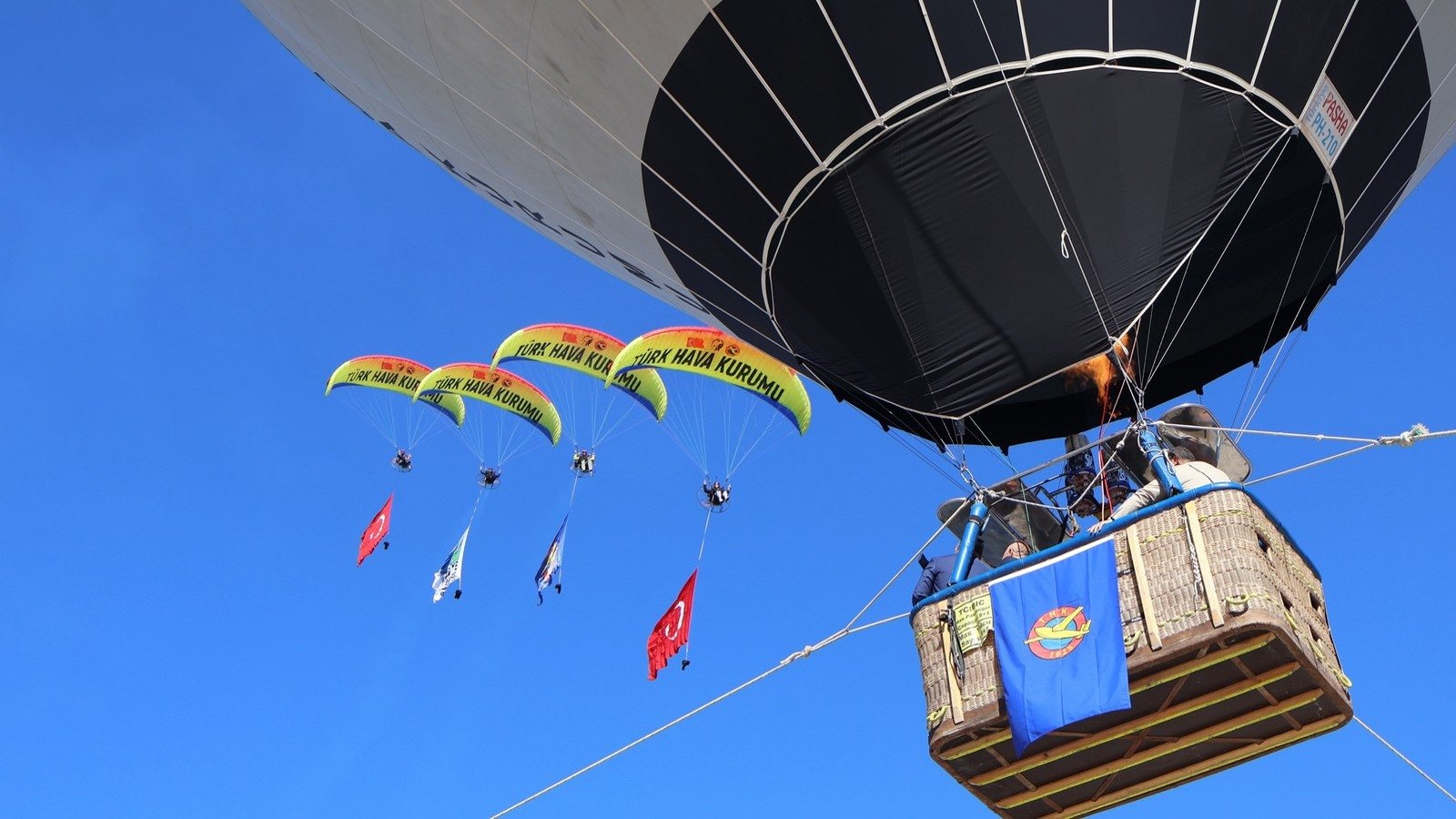 Paramotor pilotları Türk Hava Kurumu sıcak hava balonunun yanında uçuyor