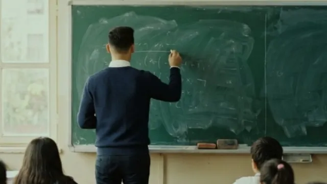 Sınıfta tahtaya yazı yazan öğretmen