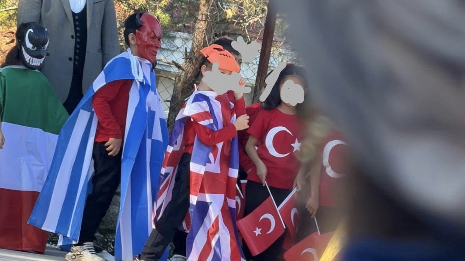 Fethiye'de bir ilkokulun 29 Ekim gösterisinde farklı ülke bayrakları ve maskelerle öğrenciler